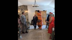 (ВИДЕО) Го изненадила младоженецот – Никогаш порано не сте виделе ваква невеста: Британката Лорен прошетала до олтарот во костим на диносаурус